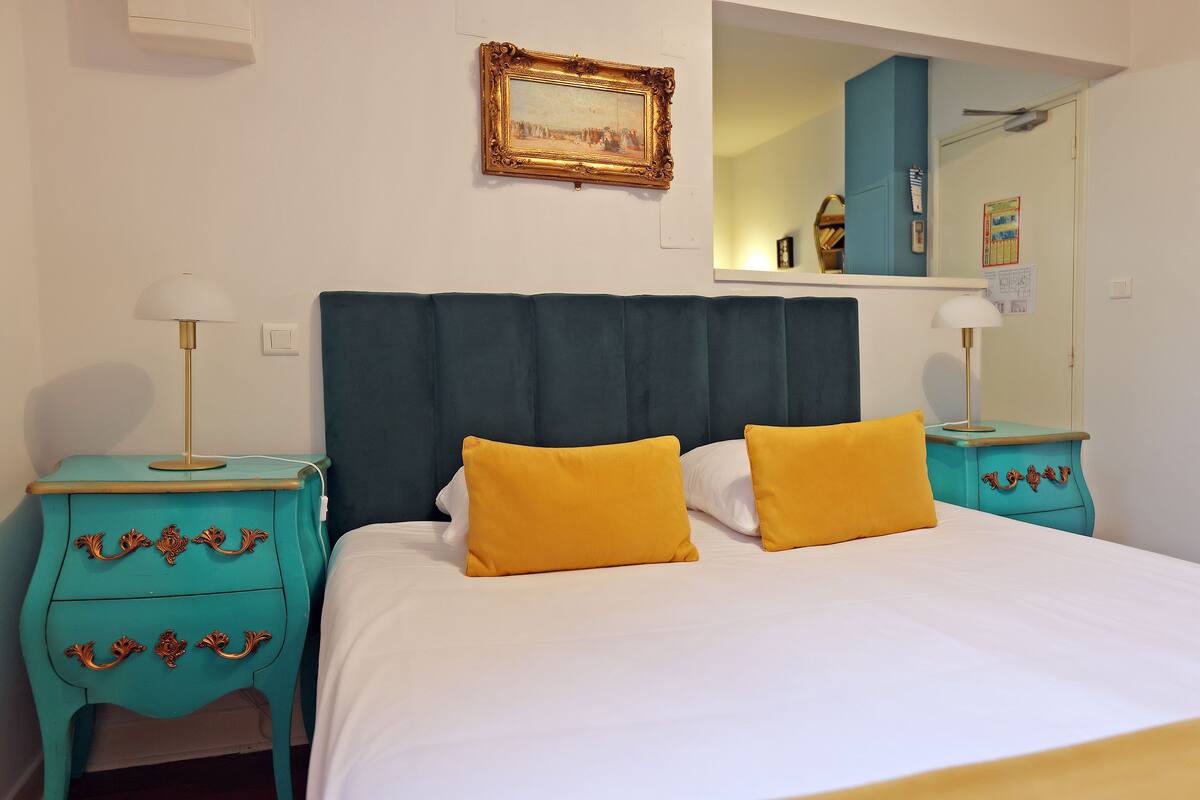 A bedroom with a bed, two nightstands, a dresser, a mirror, and a framed picture on the wall.