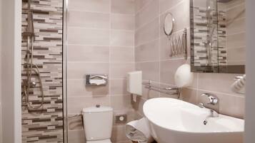 Un baño moderno con ducha de vidrio, inodoro y lavabo con espejo.