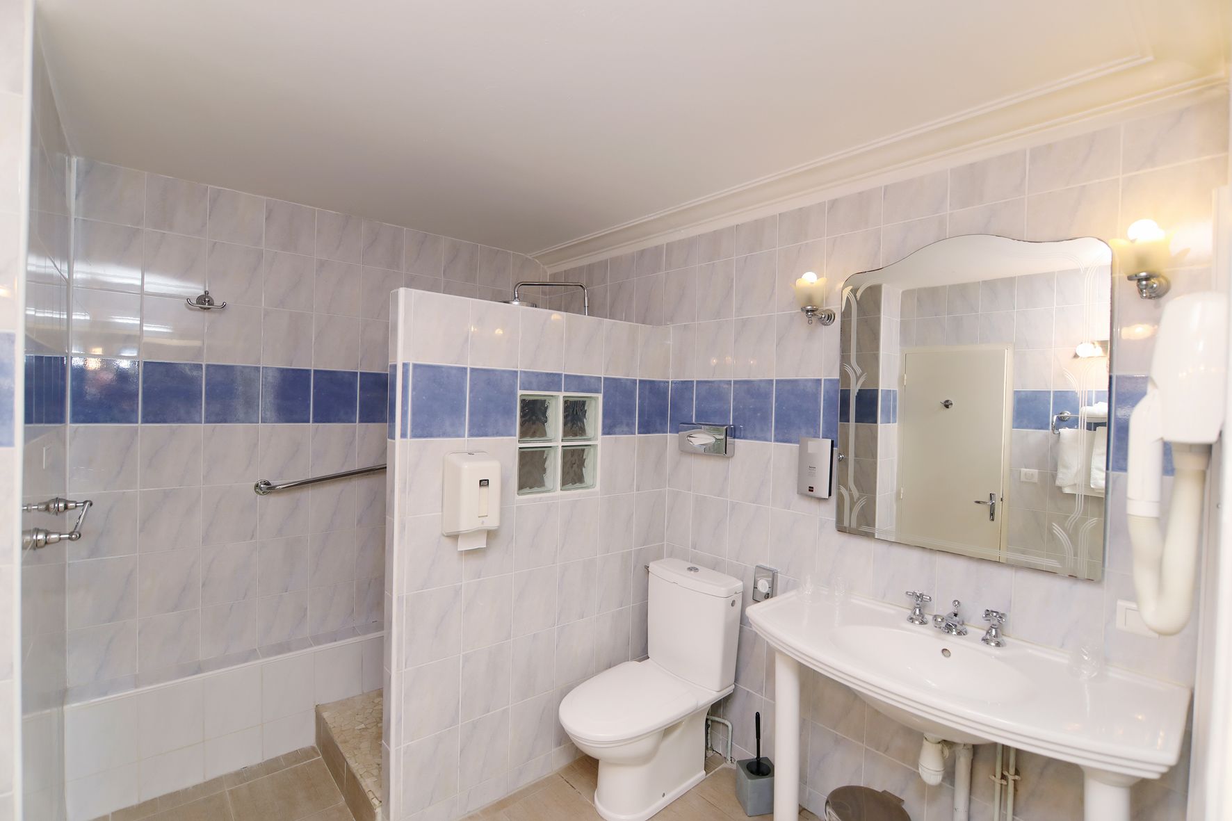 A modern bathroom with a shower, toilet, sink, and a large mirror.
