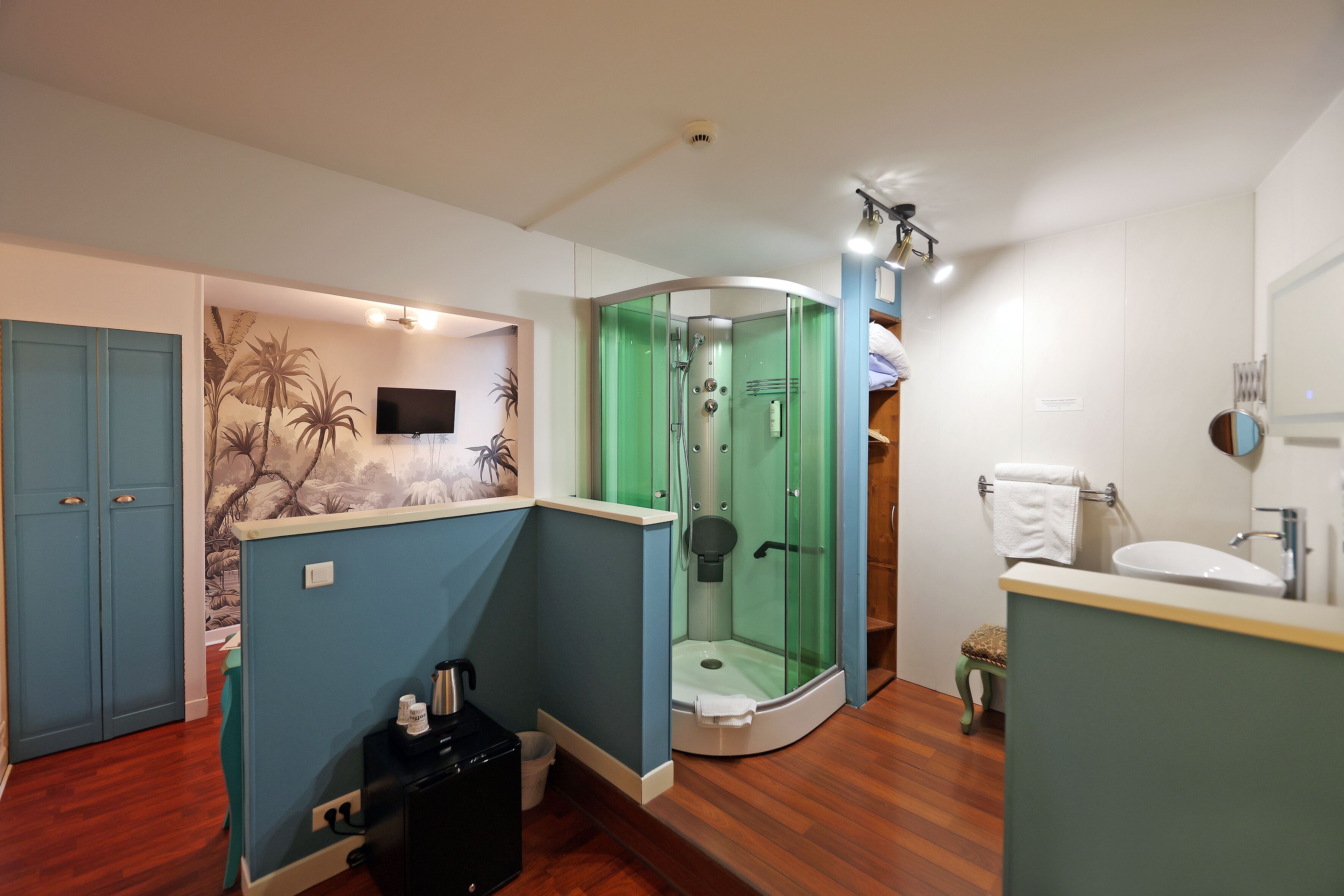 A bathroom with a shower, toilet, sink, and a TV mounted on the wall.