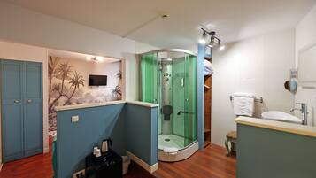 A bathroom with a shower, toilet, sink, and a TV mounted on the wall.