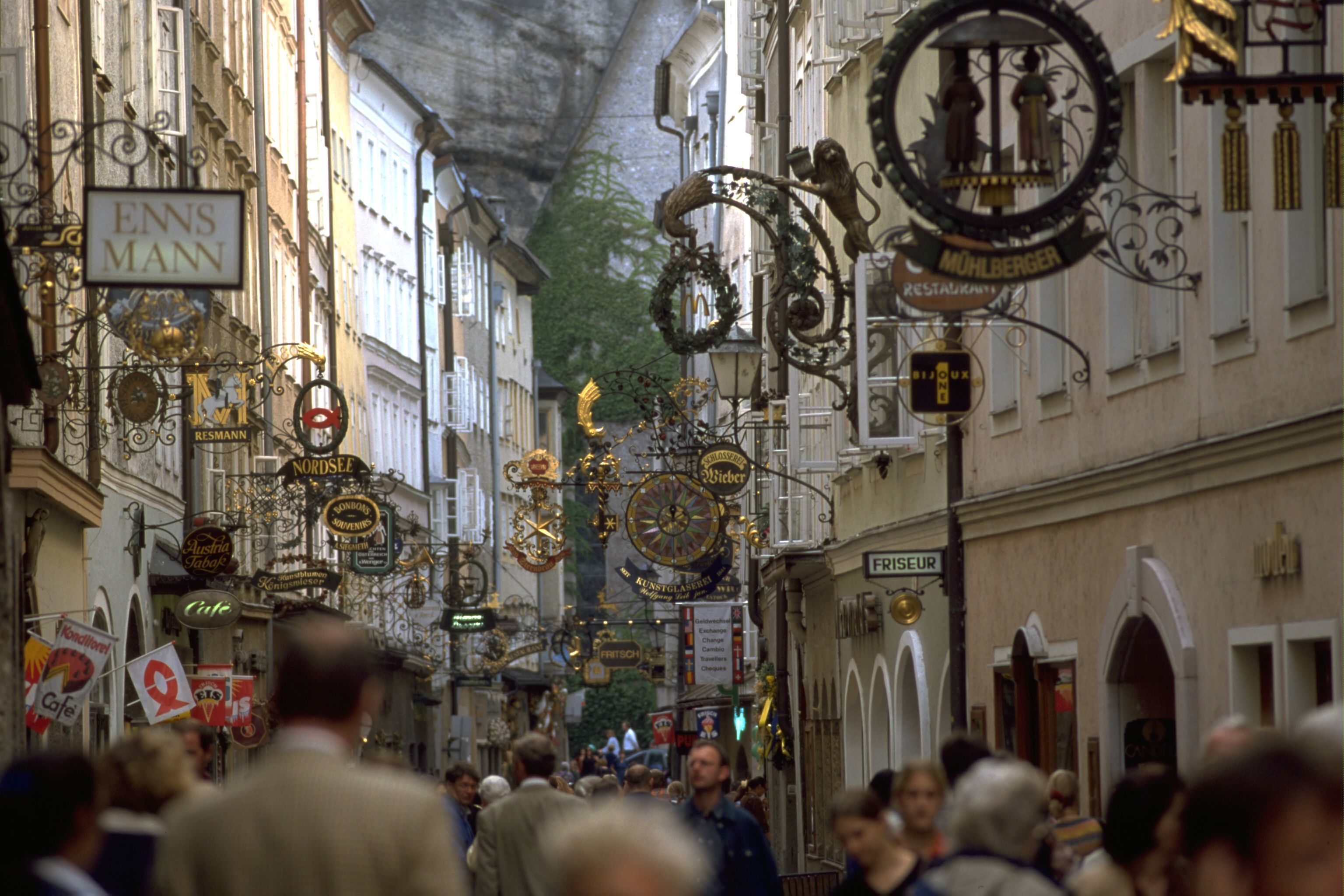 Una calle concurrida con letreros ornamentales y una multitud de gente.