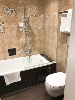 A modern bathroom with a glass-enclosed bathtub, a showerhead, a toilet, and a towel rack. - Kaiserhof Anif (Anif)