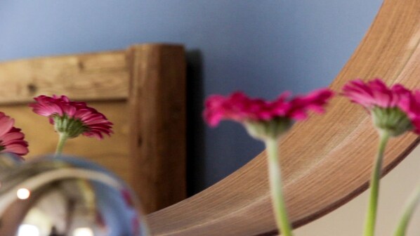 A wooden chair with a vase of pink flowers.