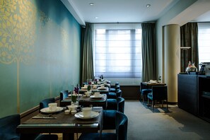 A dining area with tables set for service, a large window with curtains, and a view of the cityscape. - Hôtel Parc Saint Séverin (Paris)