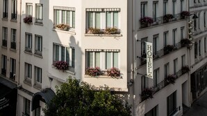 Un hotel de varios pisos con balcones, ventanas amplias y jardineras florales.