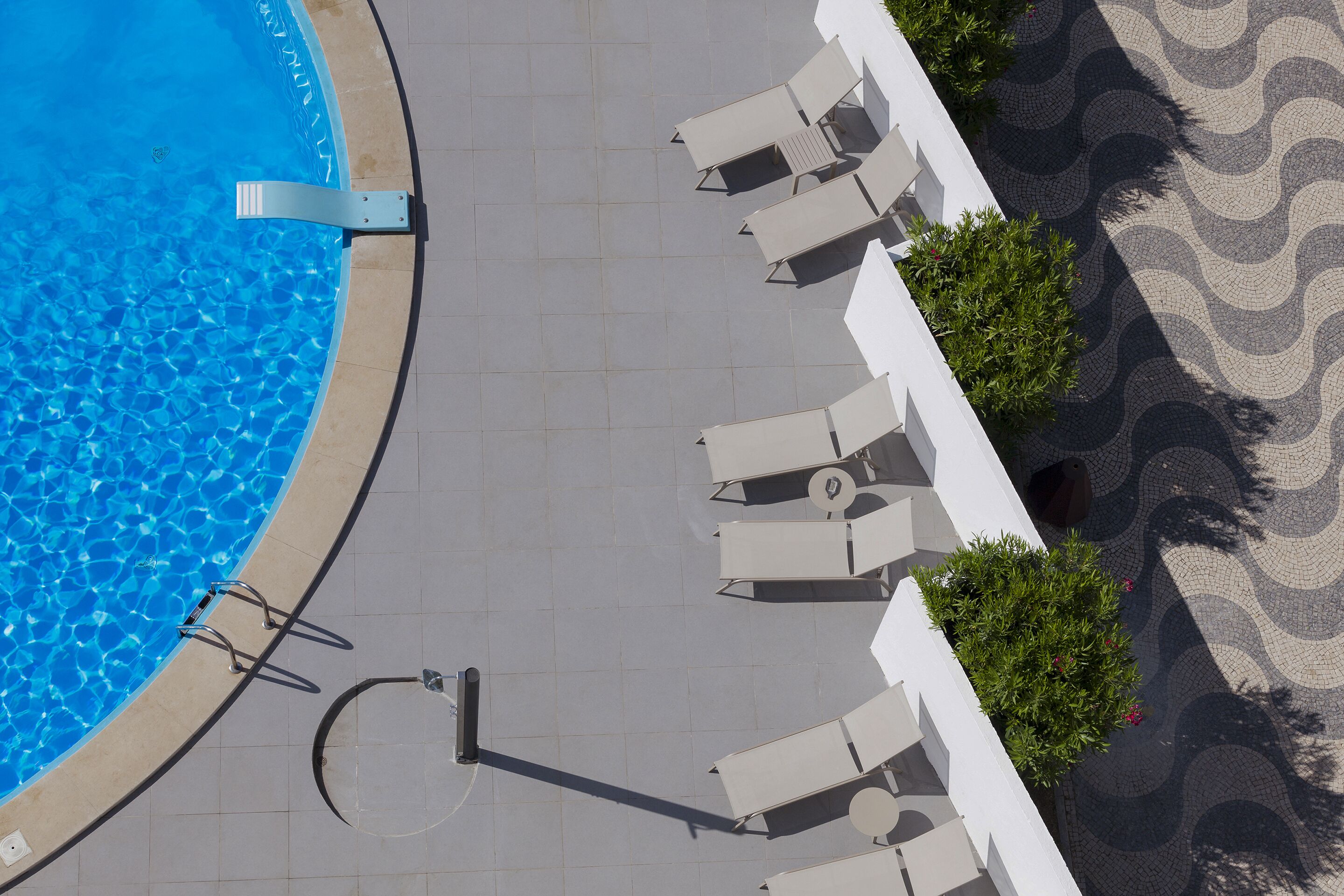 Una piscina con lettini da sole e un percorso pedonale piastrellato.