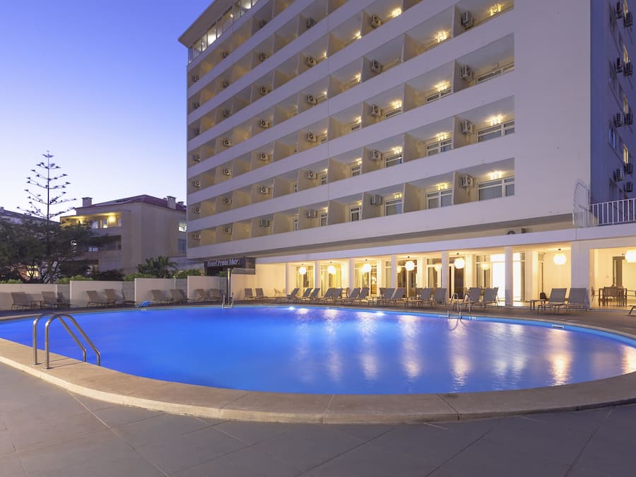A hotel with a swimming pool, multiple balconies, and outdoor seating areas.