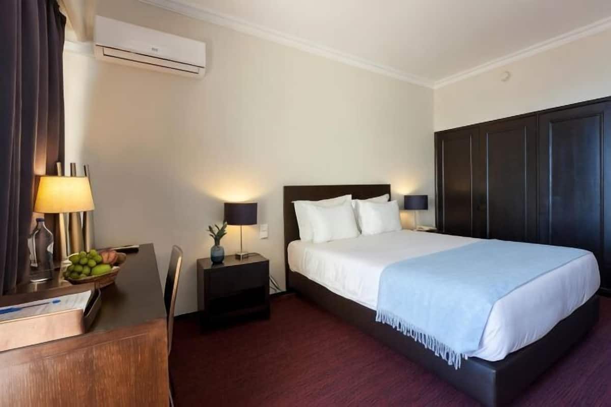 Camera d'albergo con un letto, comodini, una scrivania e un climatizzatore.