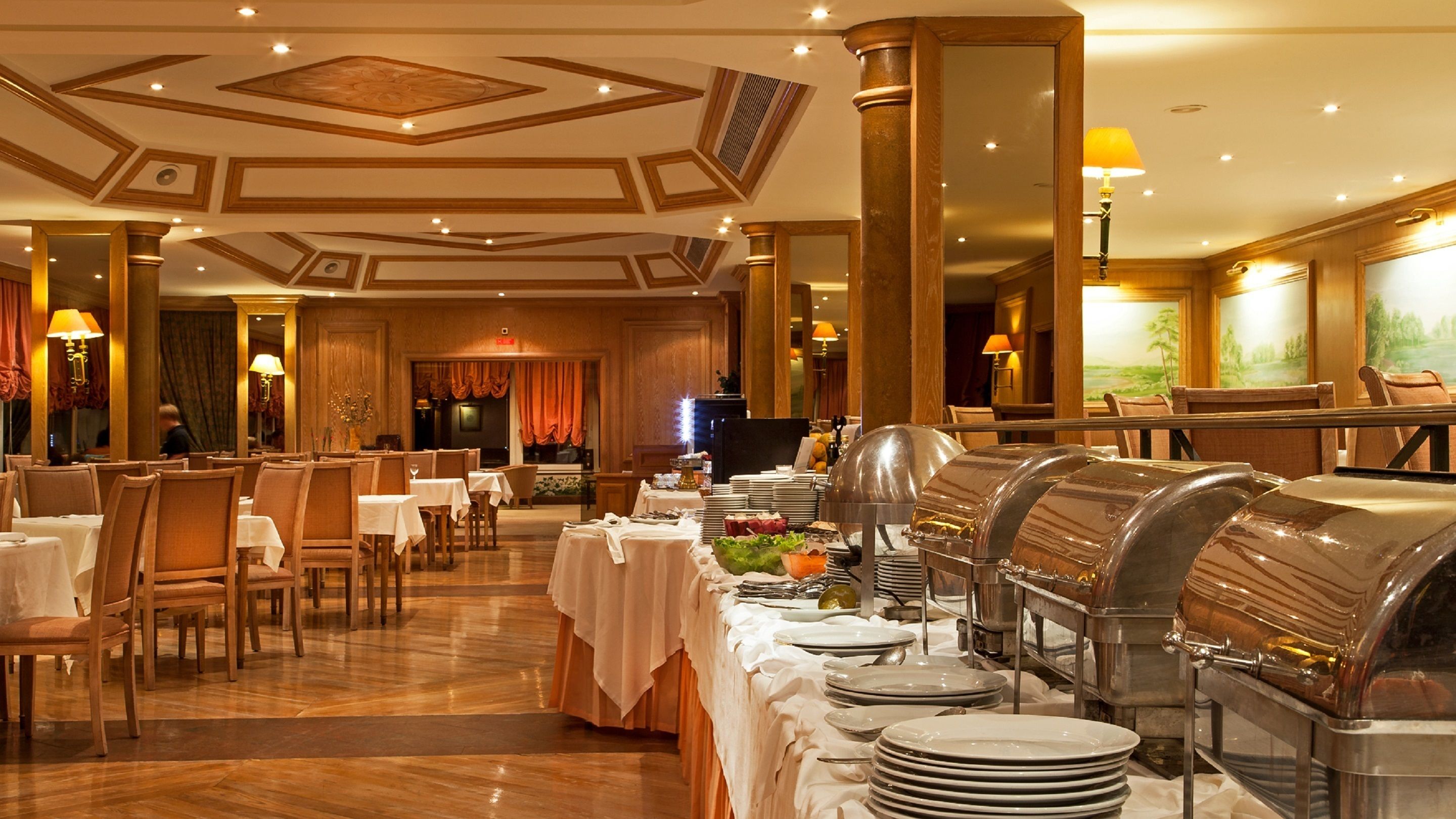 A formal dining area with tables set for service, a buffet station, and a large mirror reflecting the room.