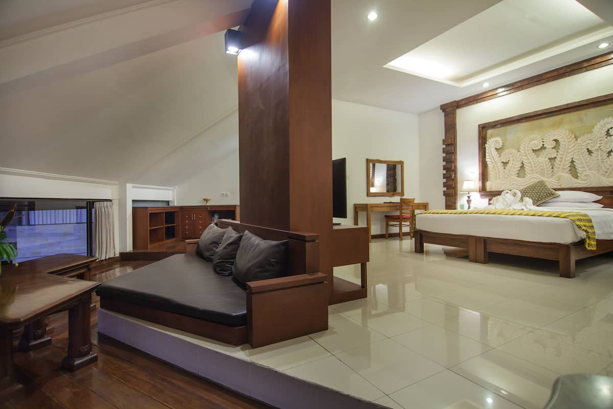 A spacious living area with a sofa, a dining table, and a large bed with a decorative headboard.