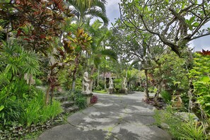A garden pathway with statues and lush greenery. - Bali Spirit Hotel & Spa (Ubud)