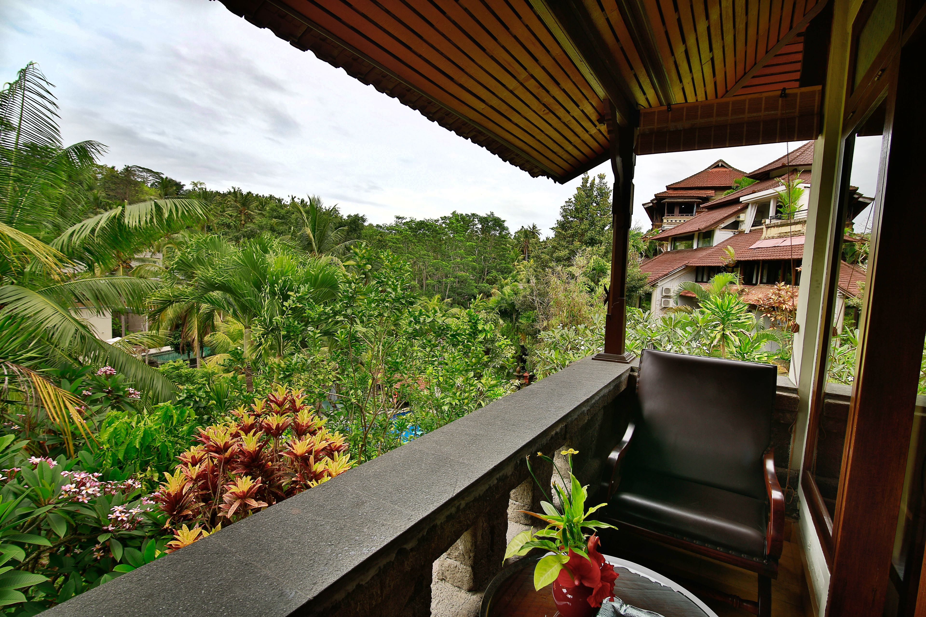 A balcony with a view of lush greenery and a building in the background.