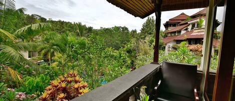 A balcony with a view of lush greenery and a building in the background.