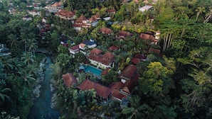 An aerial view of a residential area with houses surrounded by dense tropical vegetation and a river. - Bali Spirit Hotel & Spa (Ubud)