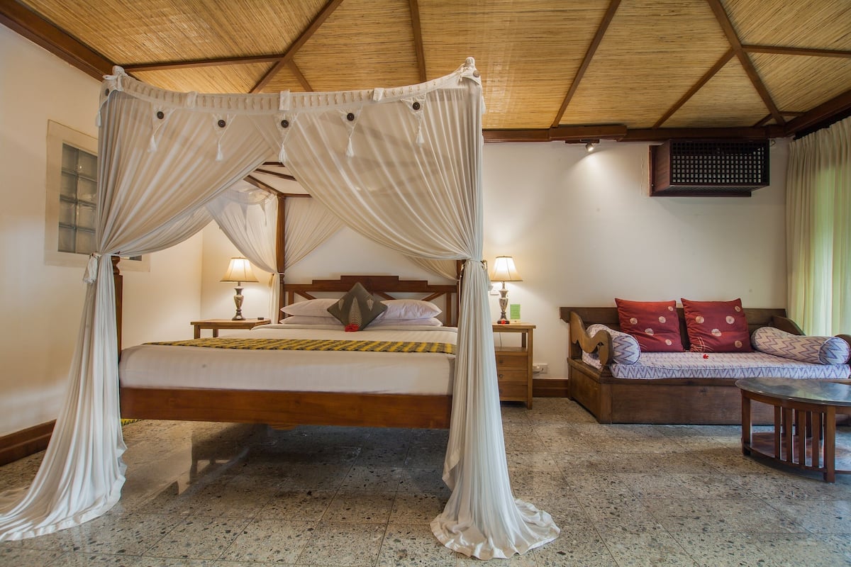 A room with a four-poster bed, a sofa, and a small table.
