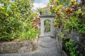 A pathway leading to a stone structure surrounded by lush greenery. - Bali Spirit Hotel & Spa (Ubud)