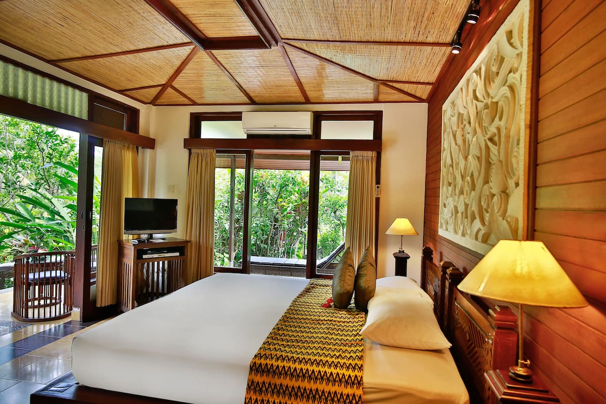 A large bed with a patterned bedspread, a television, and a wooden headboard.