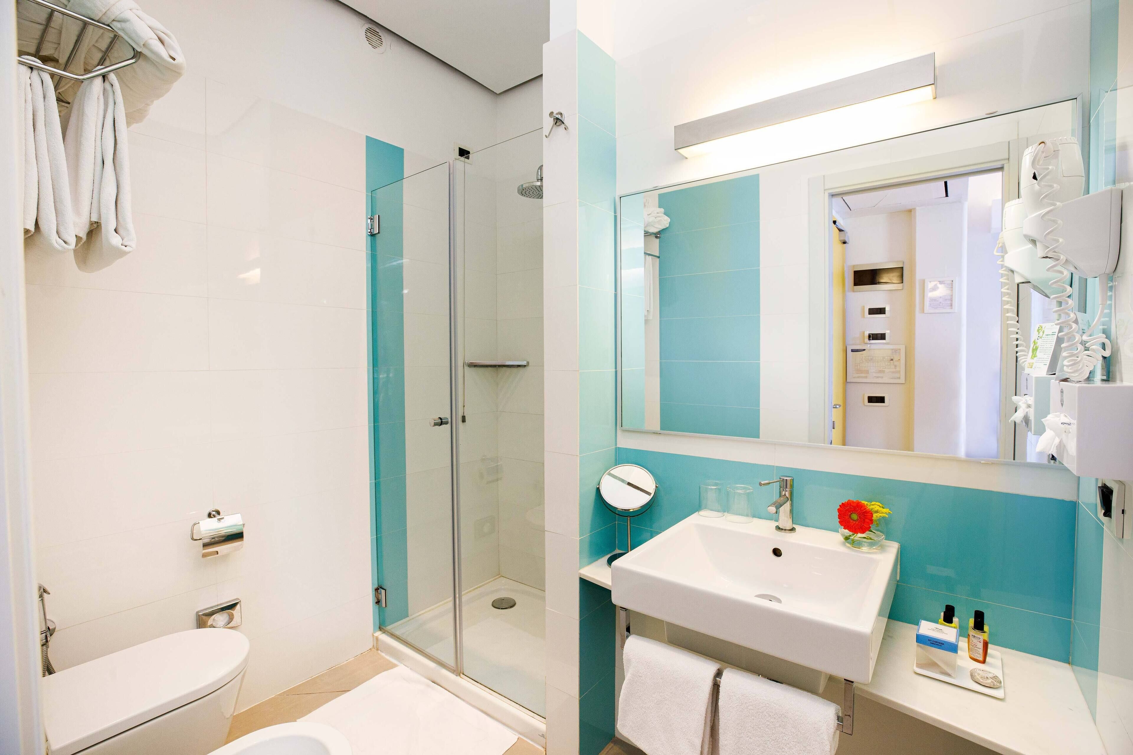A modern bathroom with a glass-enclosed shower, a white sink with a mirror, and a toilet.