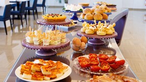Una mesa de buffet con diversos alimentos, como sándwiches, pasteles y rodajas de tomate.