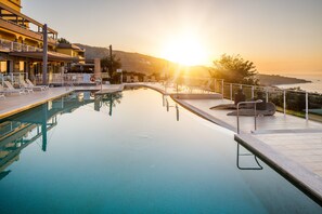 Una piscina al aire libre, sombrillas, sillones reclinables de piscina