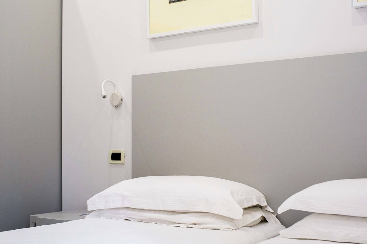 Ein Hotelzimmer mit einem Bett, einem Nachttisch und einem wandmontierten Wecker.