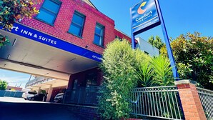 A brick building with a sign for Comfort Inn & Suites, featuring a blue awning and a clear blue sky.
