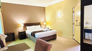 A hotel room with a bed, bedside tables, a desk, and a chair.