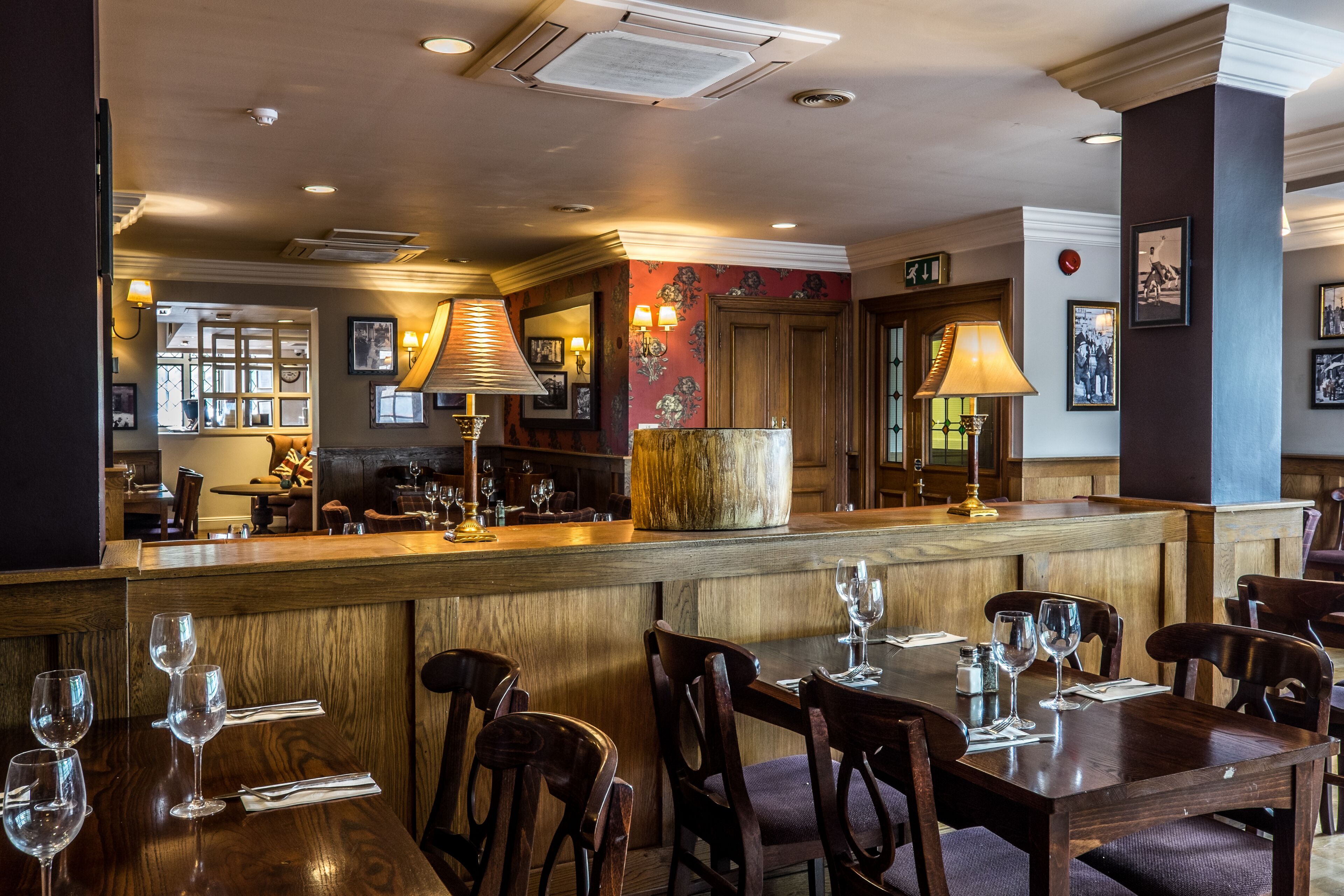 A restaurant with wooden furniture, a bar area, and framed pictures on the walls.
