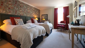 A hotel room with two beds, a desk, a chair, and a window with curtains.
