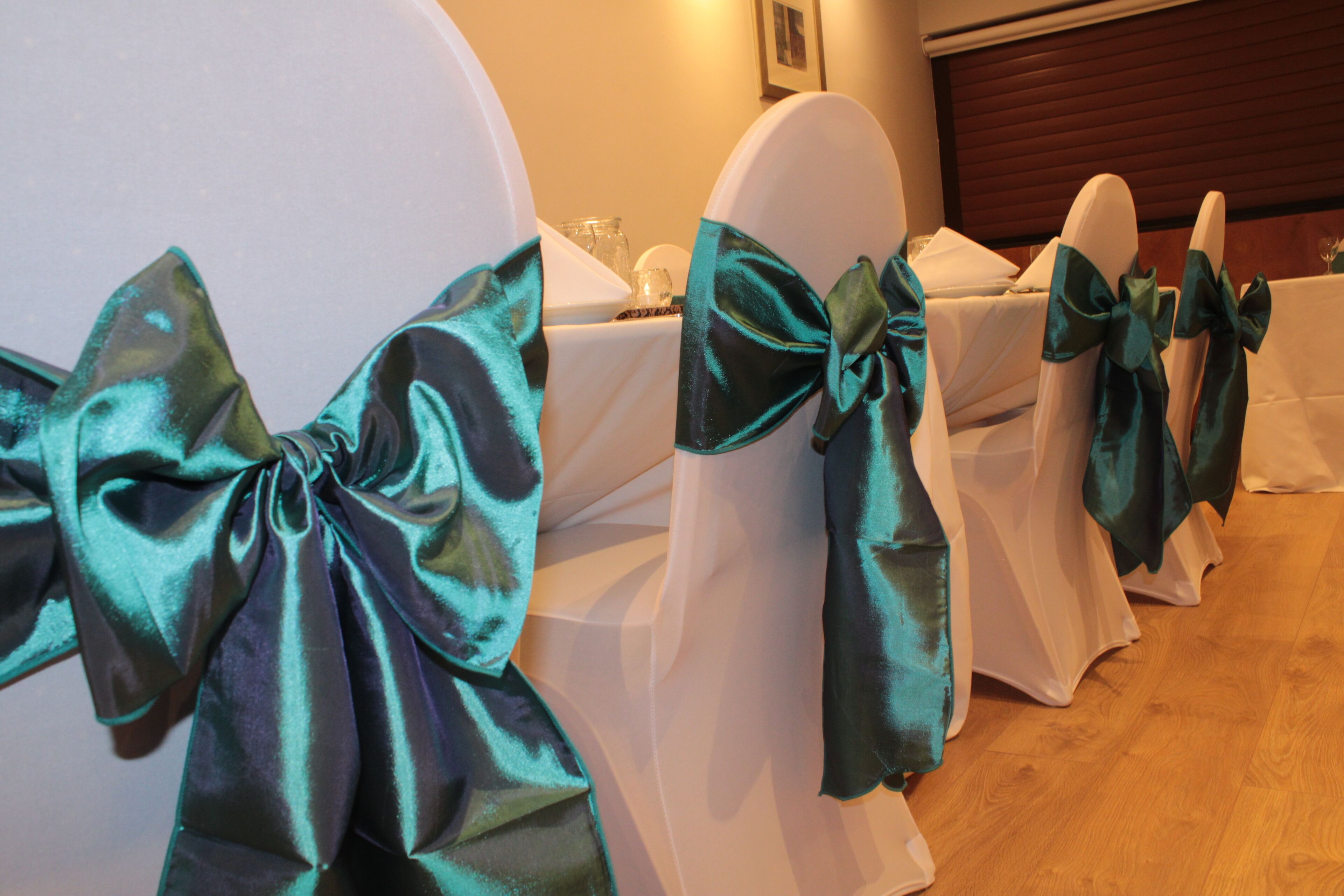 Chairs with teal bows and white tablecloths.