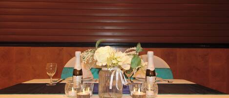 A table set with a vase of flowers, candles, and bottles of champagne.