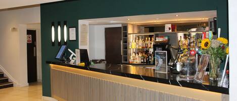 A reception area with a counter, a display of various bottles, and a signboard.