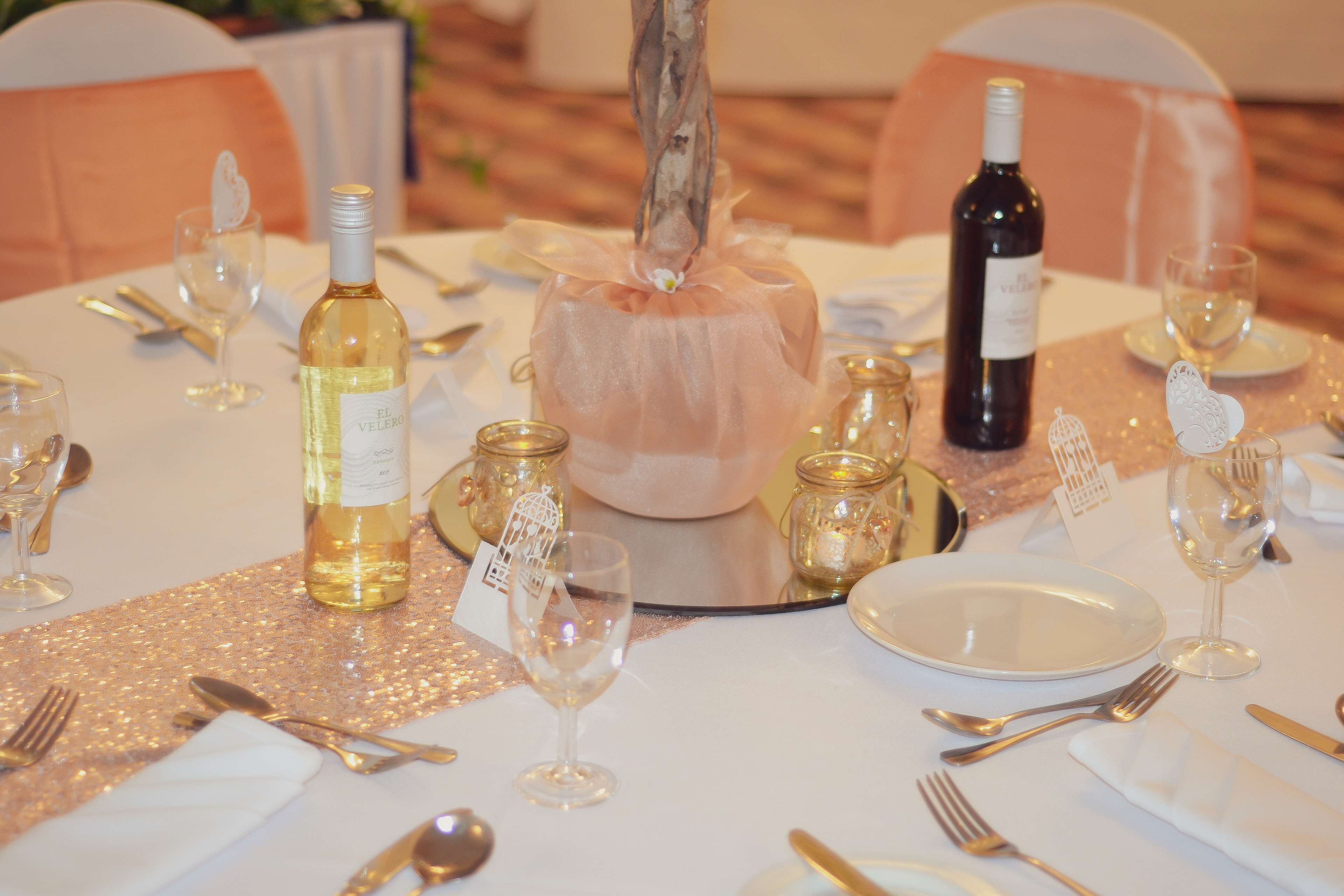 A table set for a formal event with a centerpiece, wine bottles, and glassware.