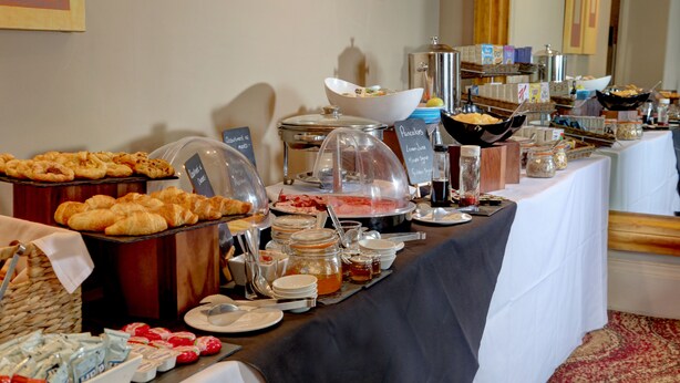 A buffet table with various food items and containers, including pastries, fruits, and beverages. - The Stuart Hotel Derby, Derby City Centre, Sure Collection by Best Western (Derby)