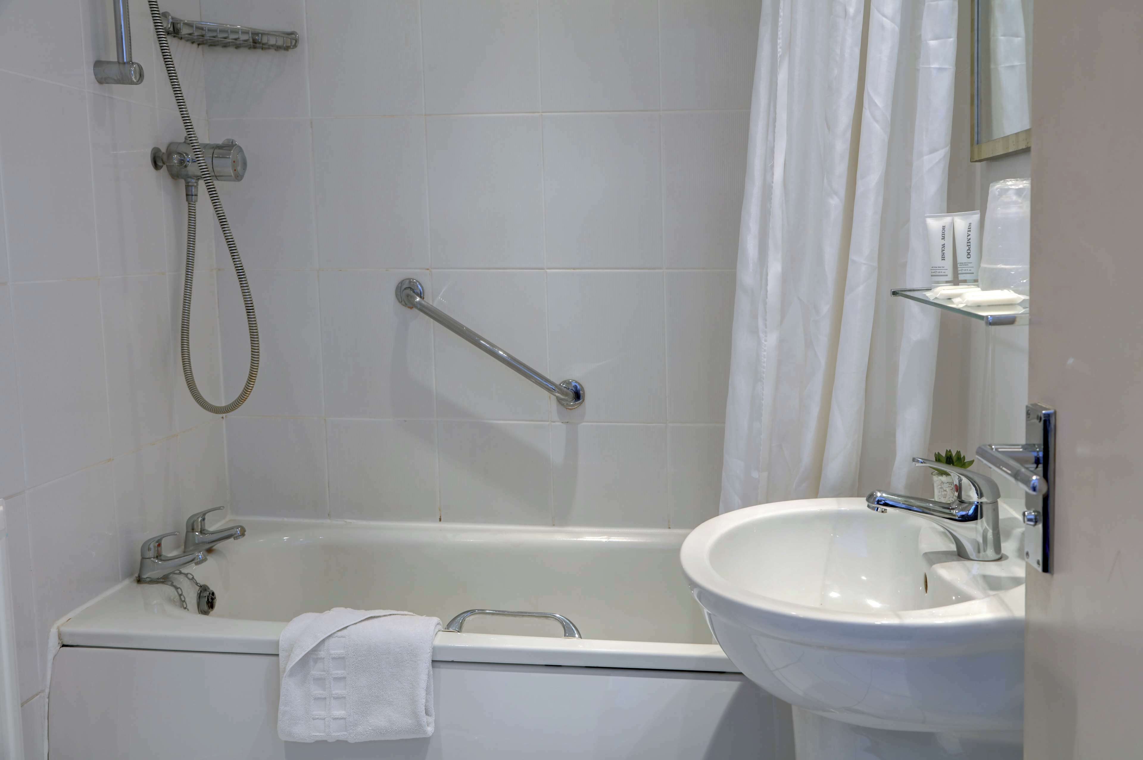 Een badkamer met een bad, een douche, een wastafel en een spiegel.