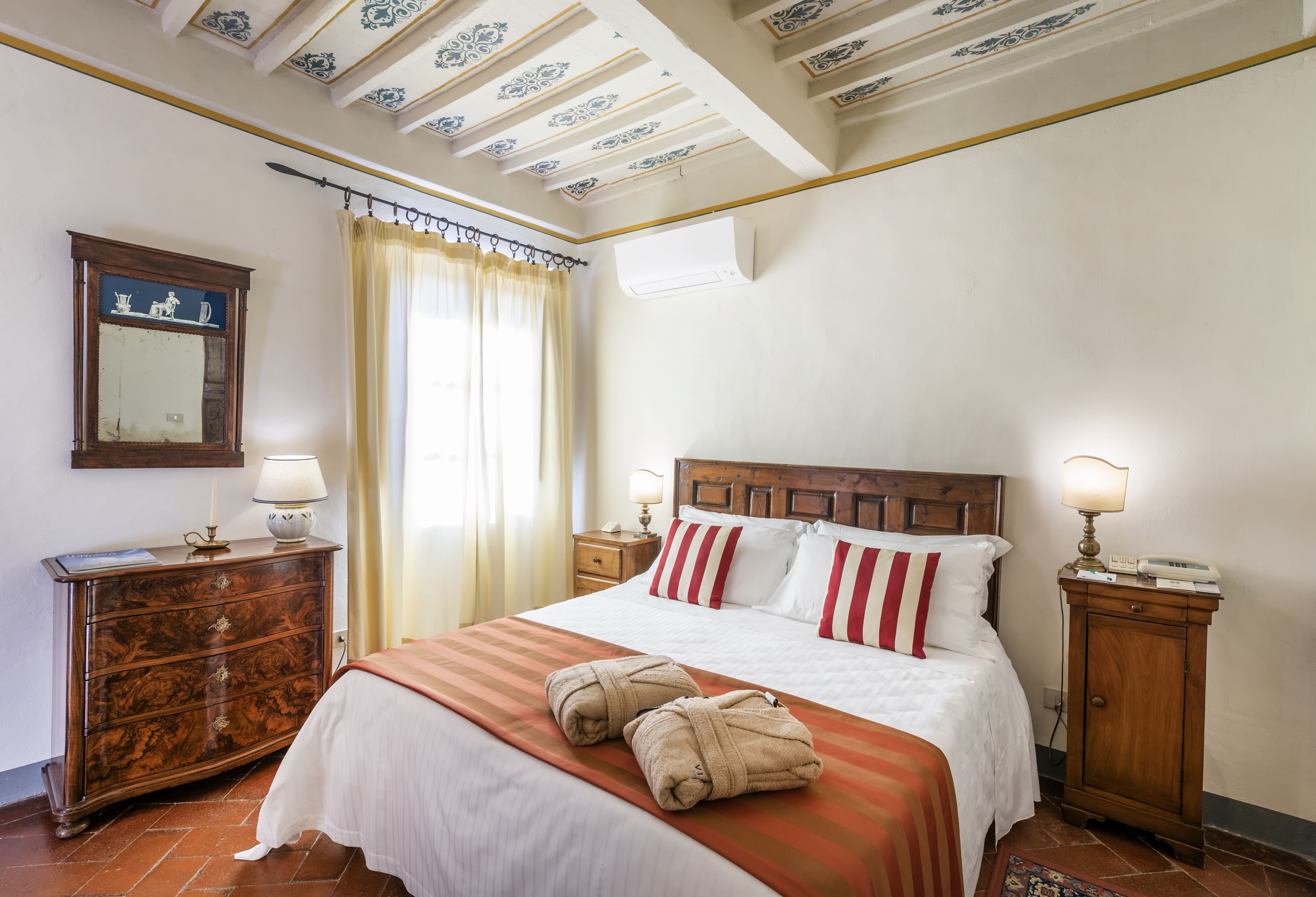 A hotel room with a large bed, wooden headboard, a dresser, a mirror, and a ceiling with decorative moldings.