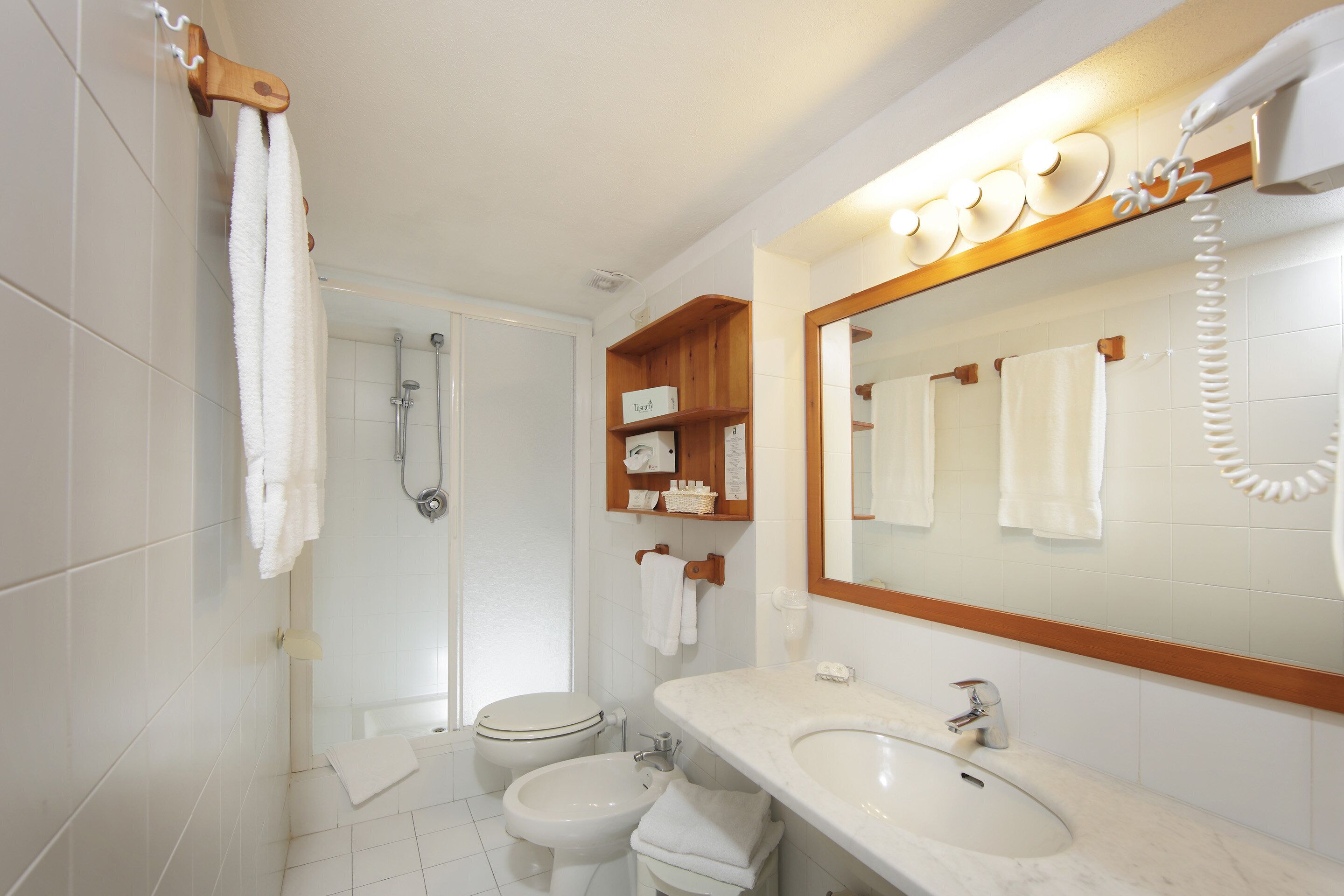 Ein Badezimmer mit Toilette, Bidet, Waschbecken und Spiegel mit Handtuchhalter.
