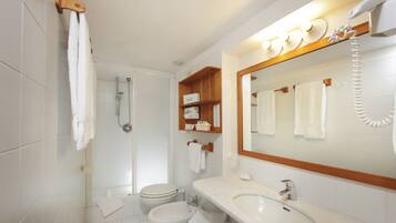 Ein Badezimmer mit Toilette, Bidet, Waschbecken und Spiegel mit Handtuchhalter.