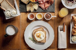 A breakfast setting with toast, eggs, cheese, and various spreads on a wooden table.