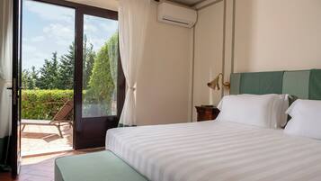 A hotel room with a bed, a nightstand, a lamp, and a view of the outdoors.