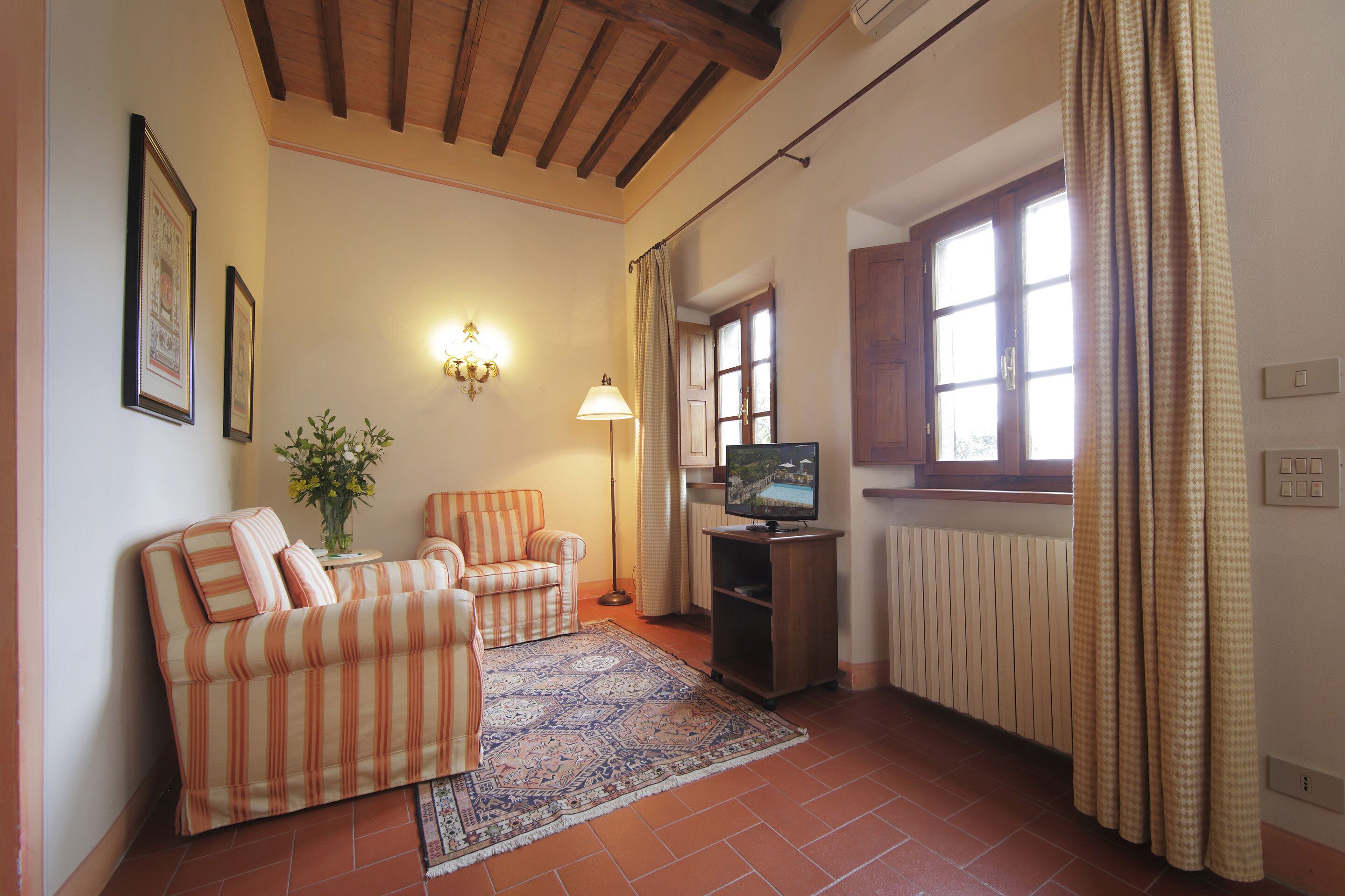 Una sala de estar con sofá, sillón y televisor sobre un mueble.