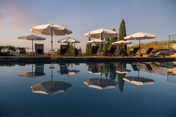 A poolside area with multiple umbrellas and lounge chairs.