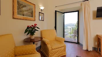 Una stanza con due poltrone gialle, un tavolino con una pianta in vaso e un'ampia finestra che si affaccia su un balcone.