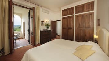 A hotel room with a large bed, wooden wardrobe, and a view of the outdoors.