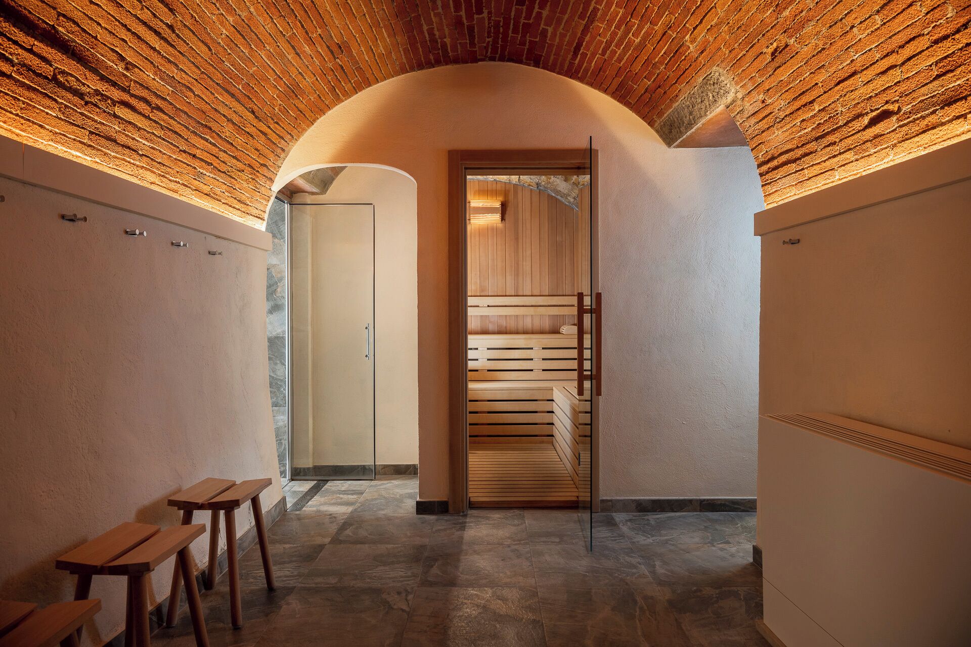 A hallway with a wooden ceiling, a sauna room, and wooden benches.
