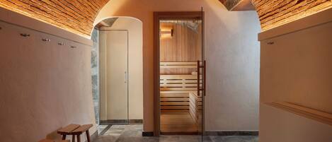 A hallway with a wooden ceiling, a sauna room, and wooden benches.