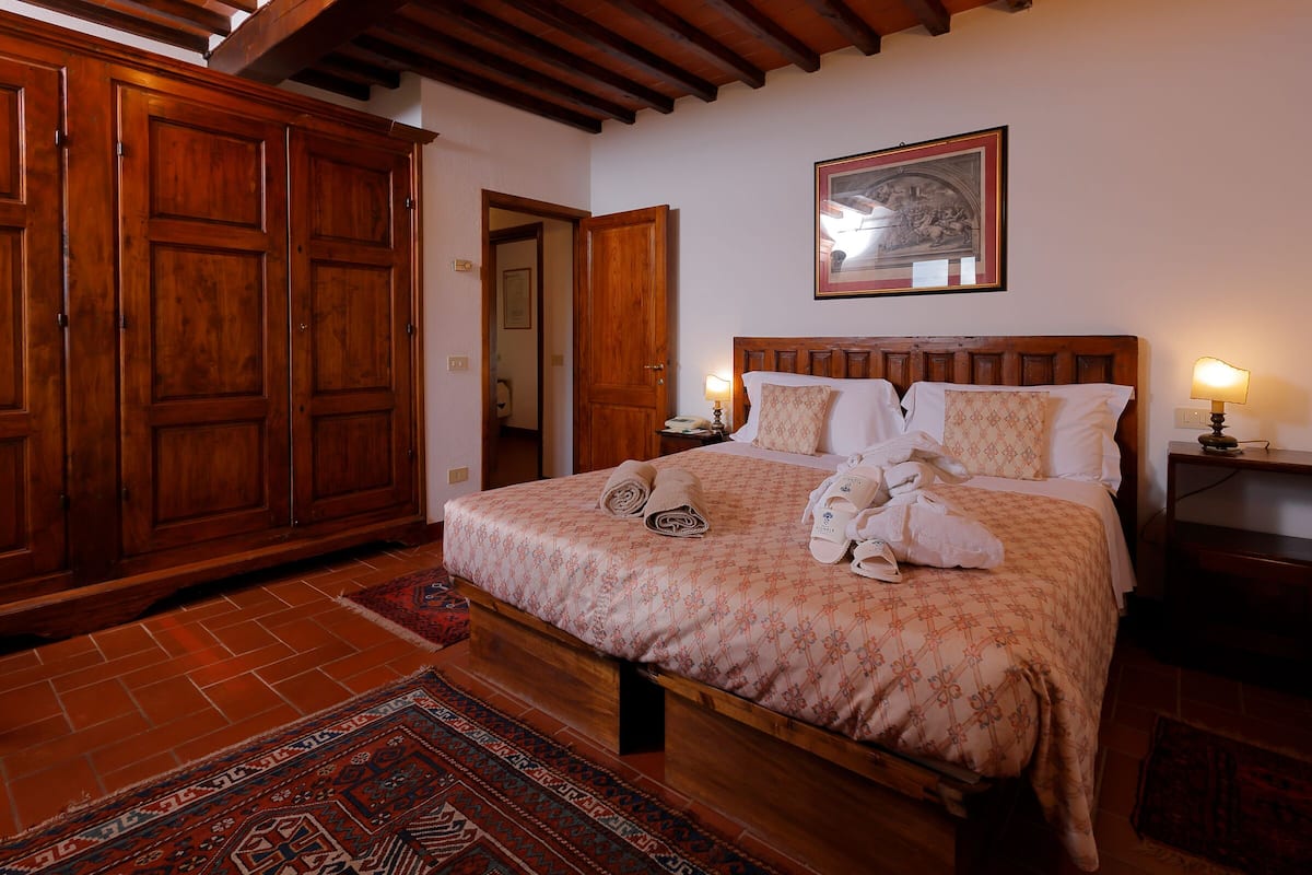 A bedroom with a wooden bed, a large wardrobe, and a patterned rug.