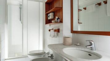 Un bagno moderno con doccia, wc, lavandino e uno scaffale in legno con articoli da toilette.