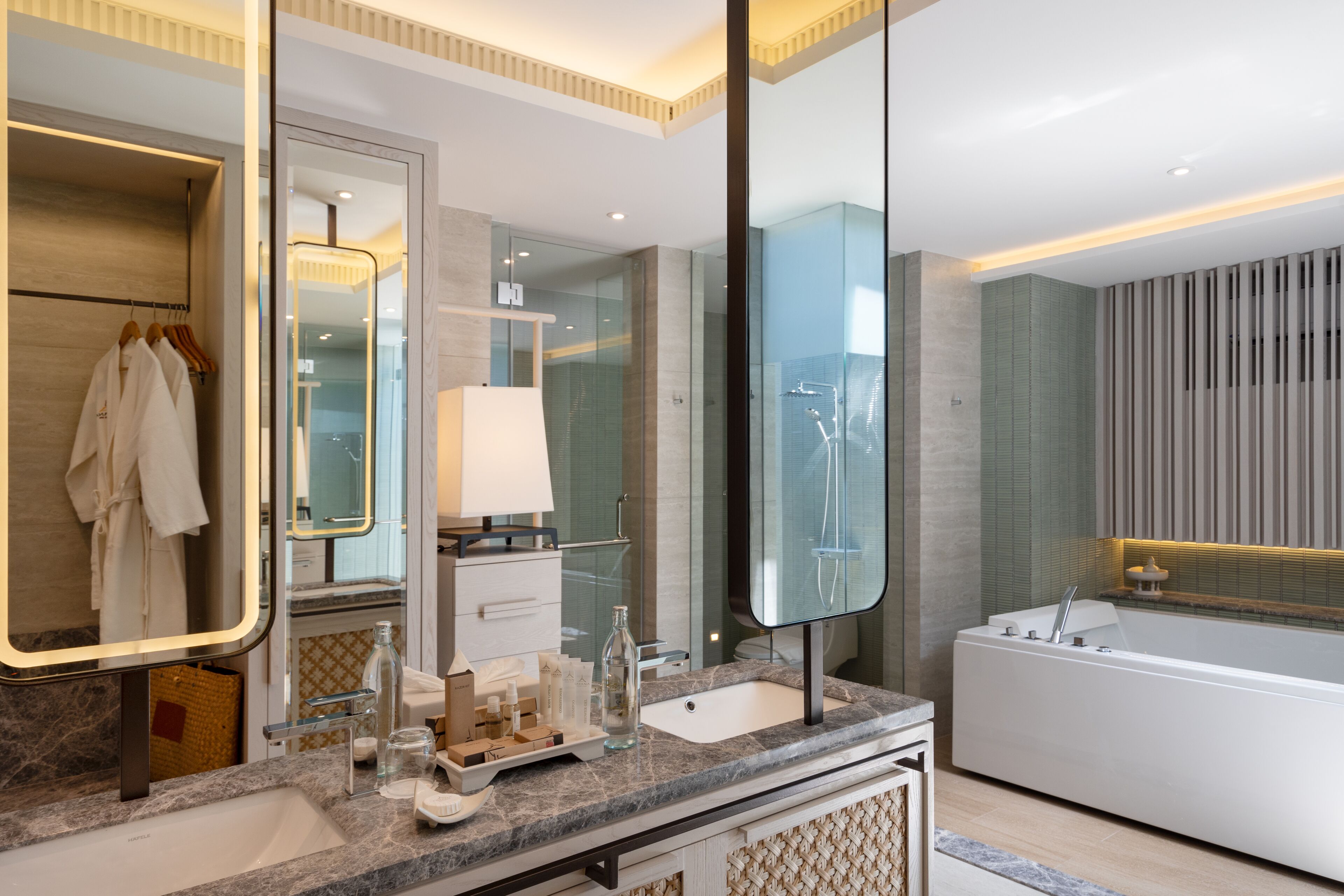 A modern bathroom with a large mirror, a bathtub, a sink, and a vanity area.